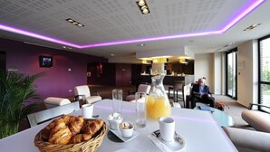 A modern dining area with a table set for breakfast, including croissants, juice, and coffee. - Relais Du Silence Domaine La Charpiniere (Saint-Galmier)