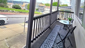A covered balcony with a table and chairs, a doormat, and a view of the street and houses. - 3 bedroom home with a view, Minutes from Downtown Pittsburgh (Pittsburgh)
