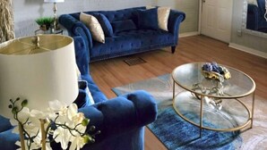A living room with a blue sofa, a glass coffee table, and a lamp. - 3 bedroom home with a view, Minutes from Downtown Pittsburgh (Pittsburgh)