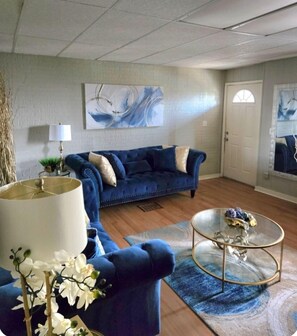 A living room with a blue sofa, a glass coffee table, and a lamp. - 3 bedroom home with a view, Minutes from Downtown Pittsburgh (Pittsburgh)