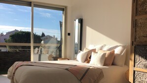 Ein Schlafzimmer mit einem großen Bett, Blick durch eine Schiebetür und einem dekorativen Holzschrank.