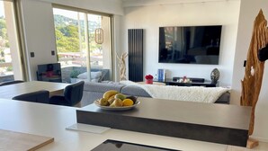 Eine moderne Küche mit Einbauherd, ein Essbereich mit Tisch und Stühlen sowie ein großes Fenster mit Blick ins Freie.