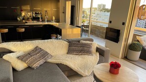 Ein modernes Wohnzimmer mit grauem Sofa, flauschigem weißen Teppich und rundem Couchtisch.