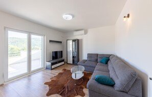 A modern living room with a grey sofa, a glass coffee table, a flat-screen TV, and a glass cabinet. - Amazing home in Muc Gornji (Muc Gornji)