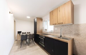 A compact kitchen with a built-in oven, a sink, and wooden cabinets. - Amazing home in Muc Gornji (Muc Gornji)