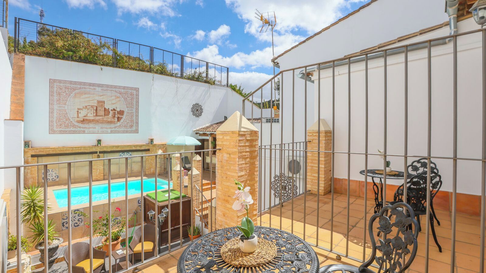 Eine Dachterrasse mit Swimmingpool, Gartenmöbeln und einer Zierwand.