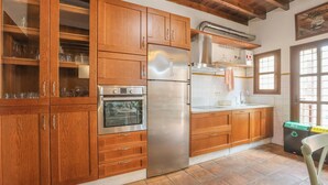 A kitchen with wooden cabinets, a stainless steel refrigerator, and an oven. - Casa Rural Andalucía Aracena by Ruralidays (Huelva)