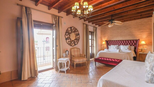 A hotel room with a bed, a chair, a table, and a chandelier. - Casa Rural Andalucía Aracena by Ruralidays (Huelva)