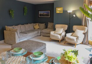 A living room with a sectional sofa, two armchairs, a coffee table, and a dining area with a table set for two. - City Centre Gem | Balcony, 2 Baths & Free Parking (Birmingham)