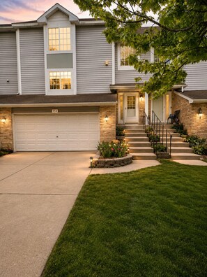 A two-story house with a garage, a front entrance with steps, and a well-maintained lawn.