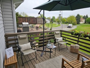 A deck with outdoor furniture, a grill, and a sign indicating local amenities. - Insurance & Workers | 5 Beds | Easy S (Grayslake)
