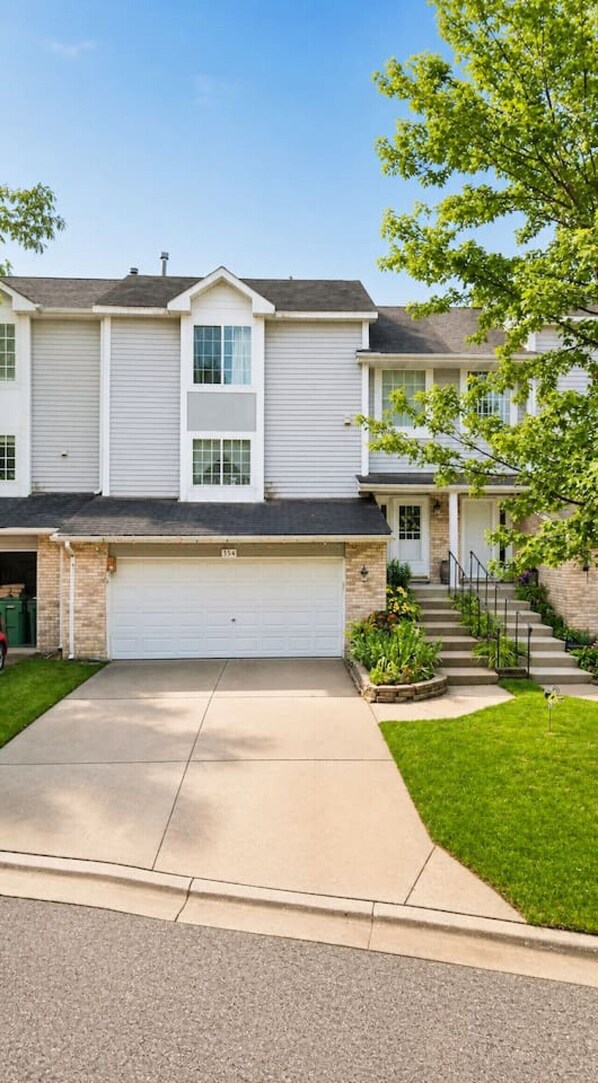 A two-story residential building with a garage, a front yard with a lawn, and a staircase leading to the entrance. - Insurance & Workers | 5 Beds | Easy S (Grayslake)