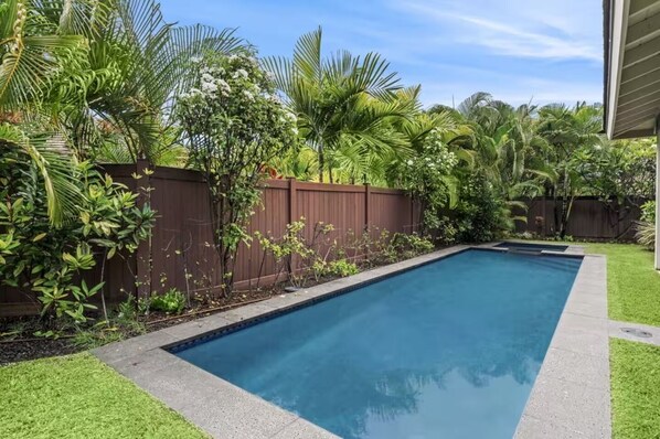 A rectangular swimming pool with a wooden fence and lush greenery. - Private Kona Home w/Private saltwater pool and spa (Kailua-Kona)