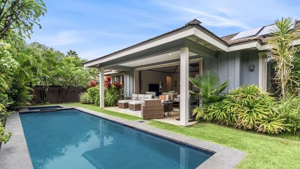 Propiedad residencial con piscina, terraza techada y abundante vegetación.
