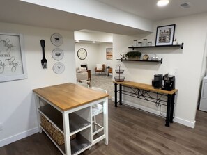 A modern kitchen with a wooden table, white cabinetry, and a black countertop. - Cozy 2BR Apartment Near Red Rocks & Mountains (Lakewood)
