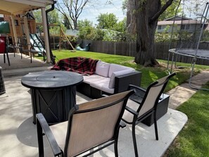 An outdoor patio with a round table, two chairs, a sofa, and a swing set. - Cozy 2BR Apartment Near Red Rocks & Mountains (Lakewood)