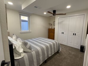 A bedroom with a bed, a ceiling fan, a window, a dresser, and a closet. - Cozy 2BR Apartment Near Red Rocks & Mountains (Lakewood)