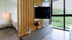 Une chambre moderne équipée d’un lit, d’une télévision, d’un globe terrestre et offrant une vue sur un paysage verdoyant.
