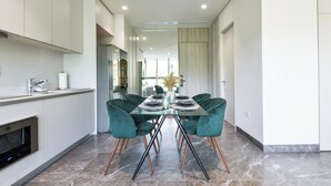 Une cuisine moderne avec un coin repas comprenant une table en verre et des chaises de couleur turquoise.