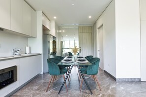 Et moderne køkken med spiseplads, komplet med et glasbord og stole i teal farve.