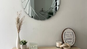 A wooden desk with a mirror, a vase with dried plants, a candle, a framed inspirational quote, and a sign with the word 'POST'. - Modern 3-Bed Home | Walk to Town & Metro | Sleeps 7 (Altrincham)