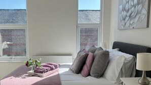 A bedroom with a bed, bedside table, and a window. - Modern 3-Bed Home | Walk to Town & Metro | Sleeps 7 (Altrincham)