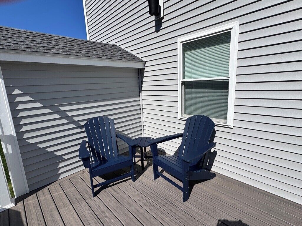 Eine Terrasse mit zwei Adirondack-Stühlen und einem kleinen Tisch.