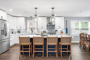 A modern kitchen with white cabinets, a central island with bar stools, and pendant lighting.