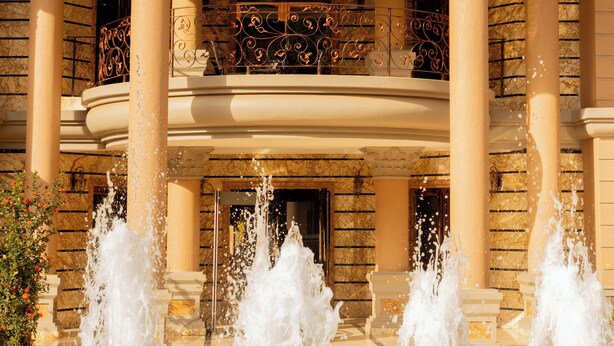 A grand building with a central fountain, ornate balconies, and classical columns. - Fountain Palace Hotel & Suites (Kampala)