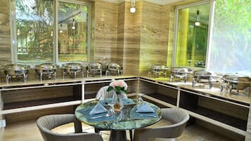 Comedor con mesa de vidrio, sillas y servicio tipo bufé con platos cubiertos.