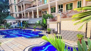 A hotel with a swimming pool, outdoor seating, and a large building with balconies. - Fountain Palace Hotel & Suites (Kampala)