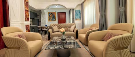 A spacious living room with a central coffee table, two sofas, and a dining area in the background.