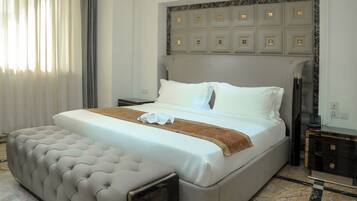 Habitación de hotel con una cama grande, una mesita de noche, una lámpara y suelo de mármol.