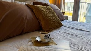 A bed with pillows, a cup of coffee, and an open book. - Skyline Sea Luxe (Thessaloniki)