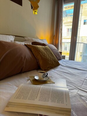 Ein Bett mit Kissen, eine Tasse Kaffee und ein offenes Buch.