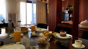 A hotel dining area with a table set for breakfast, including plates, cutlery, and a variety of pastries. - Skyline Sea Luxe (Thessaloniki)