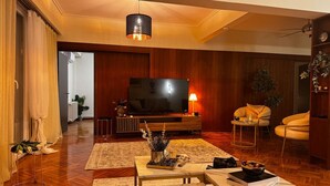 A living room with a TV, wooden furniture, a coffee table, and a sofa. - Skyline Sea Luxe (Thessaloniki)