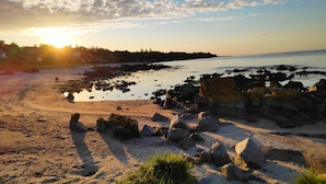 A rocky shoreline with a clear sky and the sun setting or rising. - Holiday home with sea view in Sandkaas (Allinge-Sandvig)