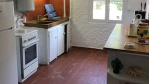 Een kleine keuken met een fornuis, spoelbak en een raam.