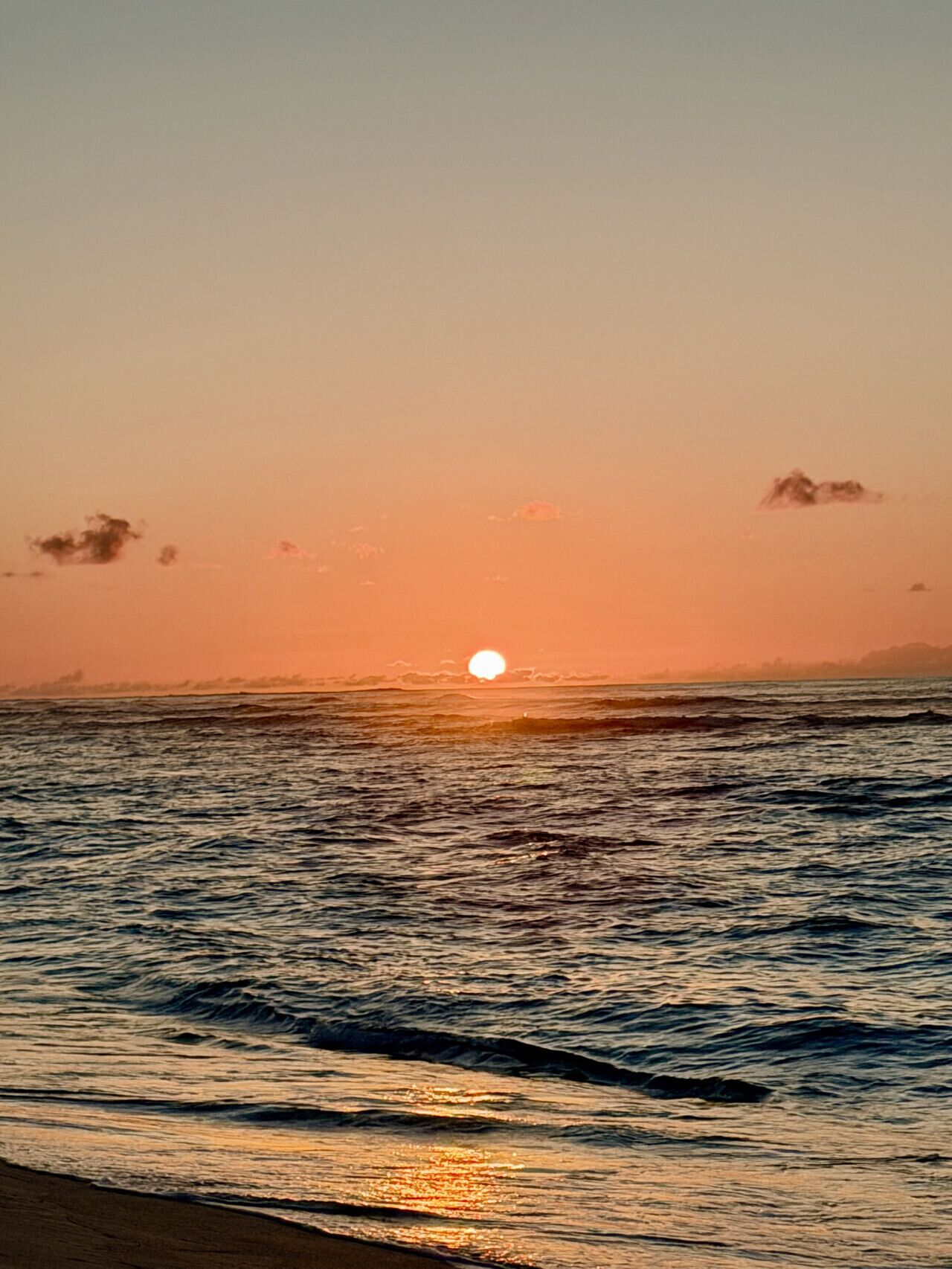 A sunset over the ocean with waves.