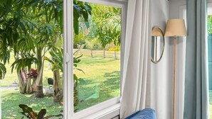 Una habitación con un ventanal grande, un sofá azul, una lámpara y una mesita.
