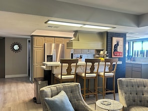 A modern kitchen with built-in appliances, a dining area with bar stools, and a decorative wall piece. - The Gilbert Rustic Hideway (Gilbert)