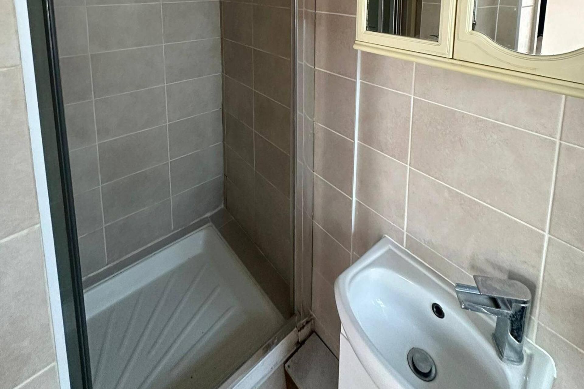 Un baño con ducha, lavamanos y espejo.