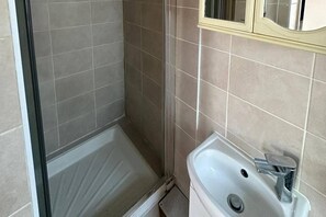 Ein Badezimmer mit Dusche, Waschbecken und Spiegel.