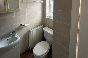 A small, compact bathroom with a white sink, toilet, and radiator. - Cozy 1 Bed Apt Sleeps 4 With Garden Views (Hounslow)