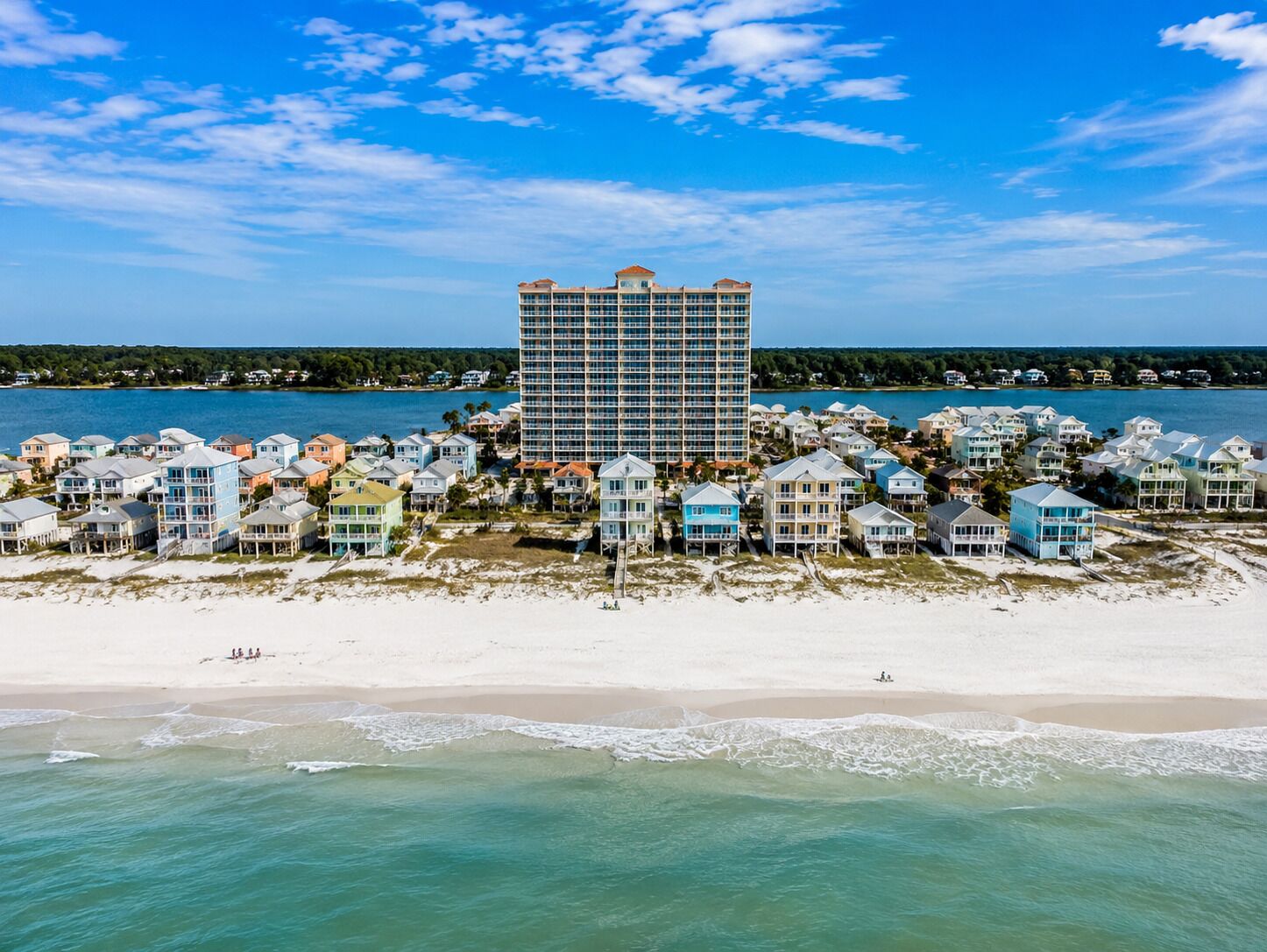 A coastal hotel with a central building surrounded by beach houses.