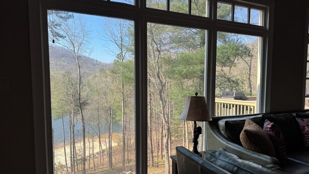 A room with large windows, a sofa, and a lamp. - Lake-Front Family Home in Big Canoe (Jasper)