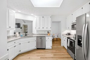 A modern kitchen with white cabinets, a dishwasher, a refrigerator, an oven, and a microwave. - Renovated Retreat w/ Game Room & Free Parking (Montgomery)