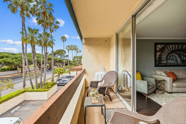 A balcony with wicker furniture, a table, and a sofa. - Ocean View La Jolla Condo - Steps to Beach (San Diego)