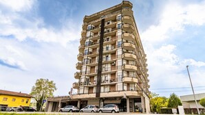 Un immeuble à plusieurs étages doté de balcons, d’un espace de stationnement et d’une devanture visible.